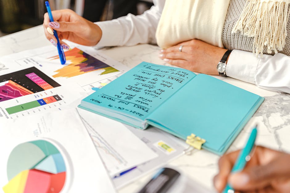 Business meeting with hands taking notes and analyzing colorful graphs and charts.